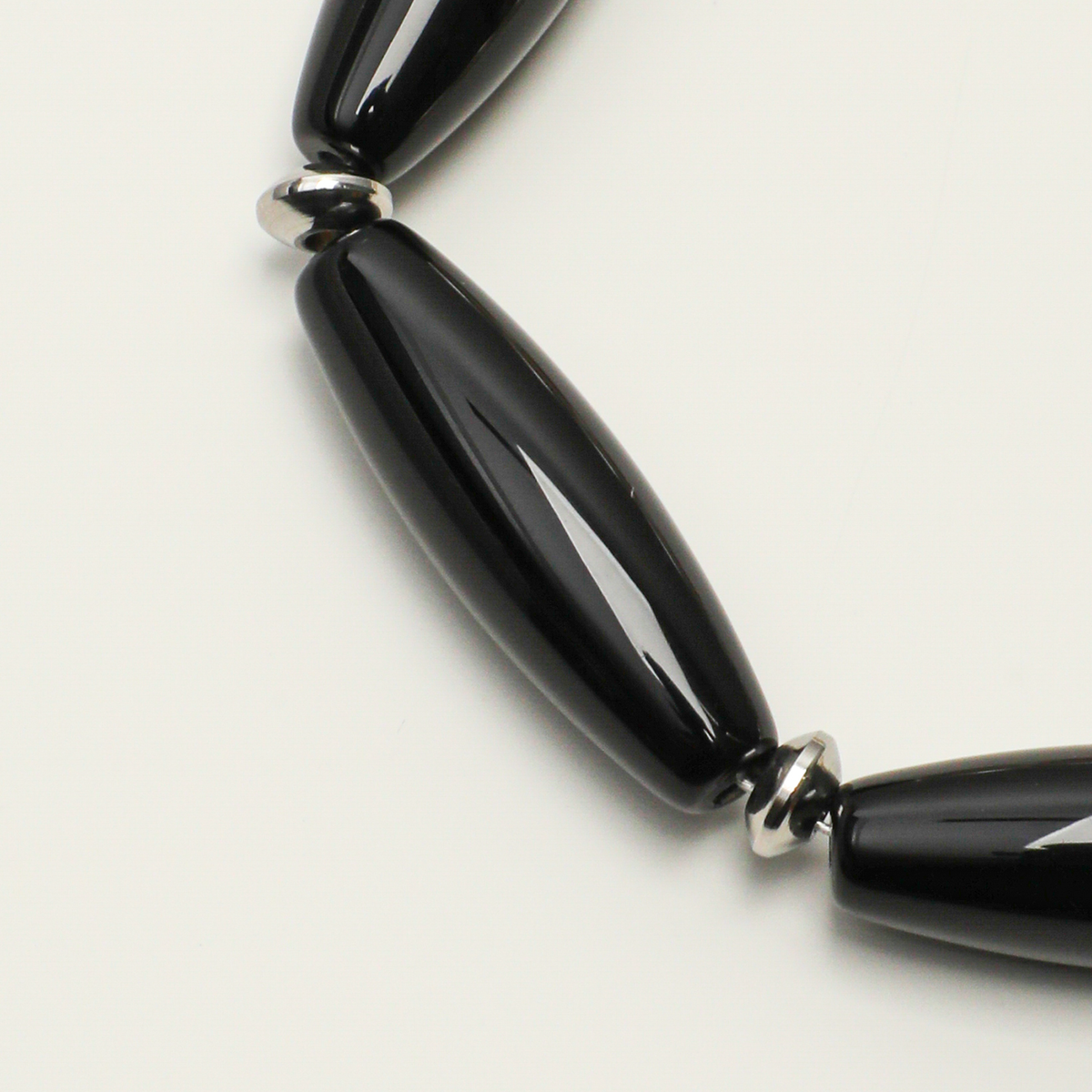 Polished black agate barrel beads and silver-tone spacer detail
